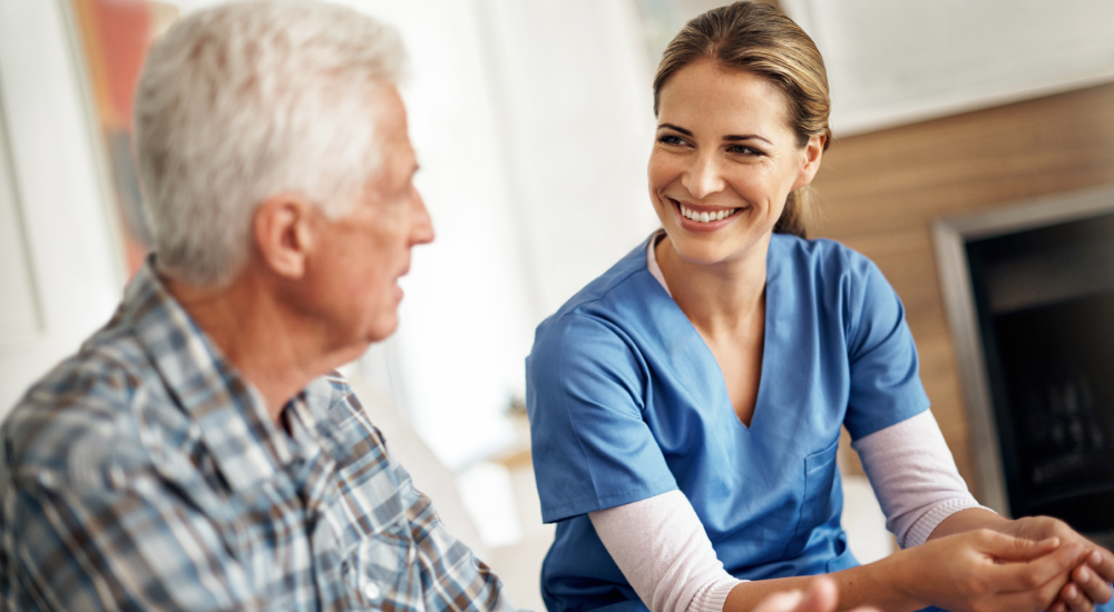 Smiling care provider talks with older care patient