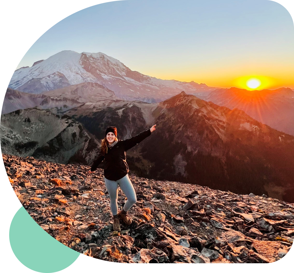 Impact-group2 A hiker standing on a mountainside at sunset with arms outstretched in triumph.