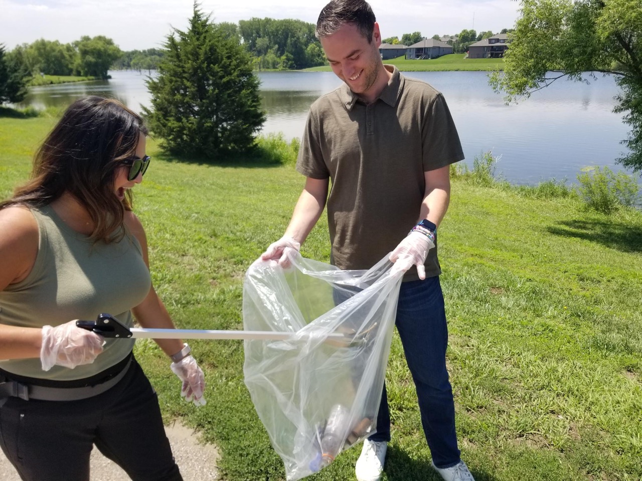 person holding a bag while another person feeds trash into it as part of community service